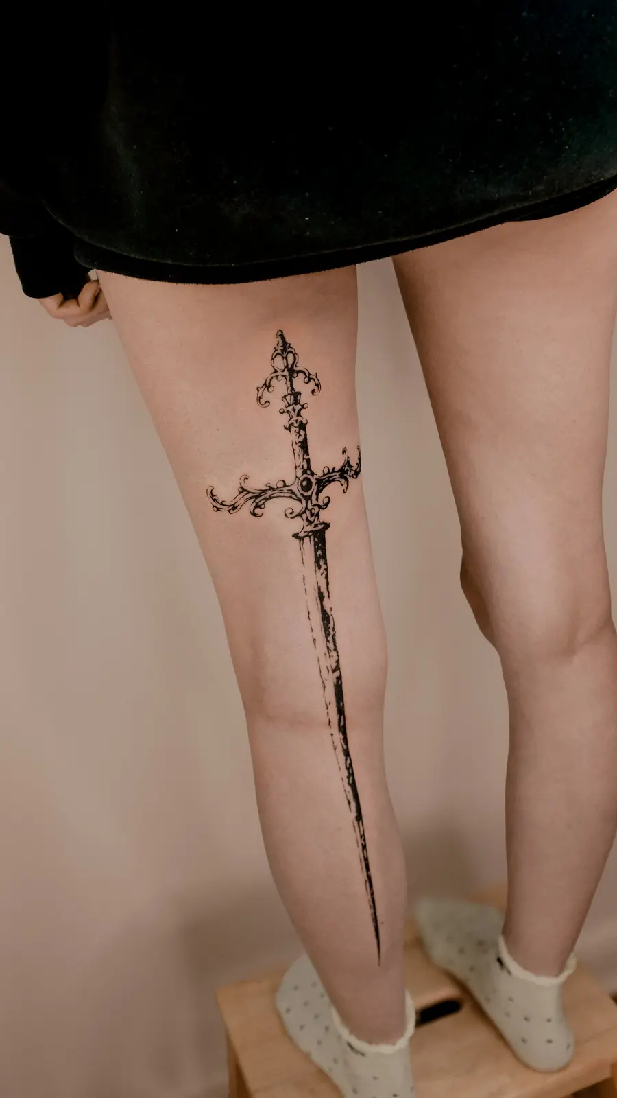Ornamental sword tattoo extending along the leg