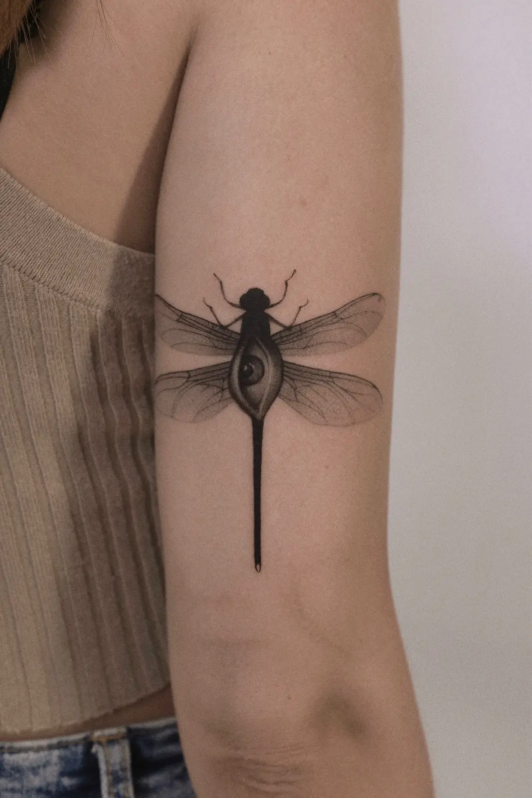 Fine line dragonfly tattoo with an eye motif