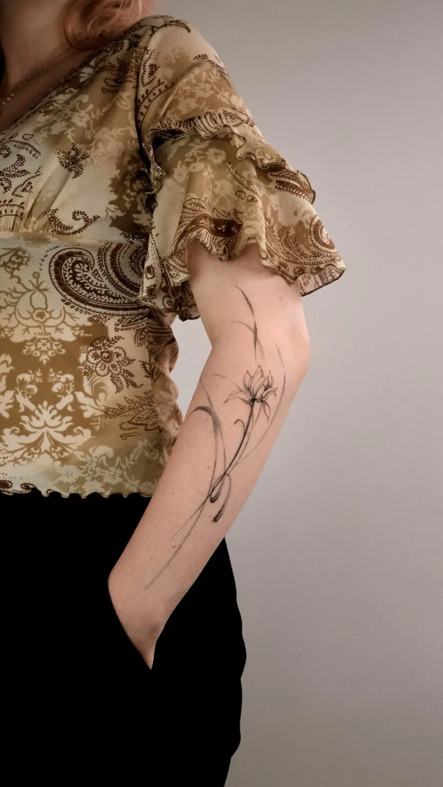 Flowing fine line flower tattoo on the arm