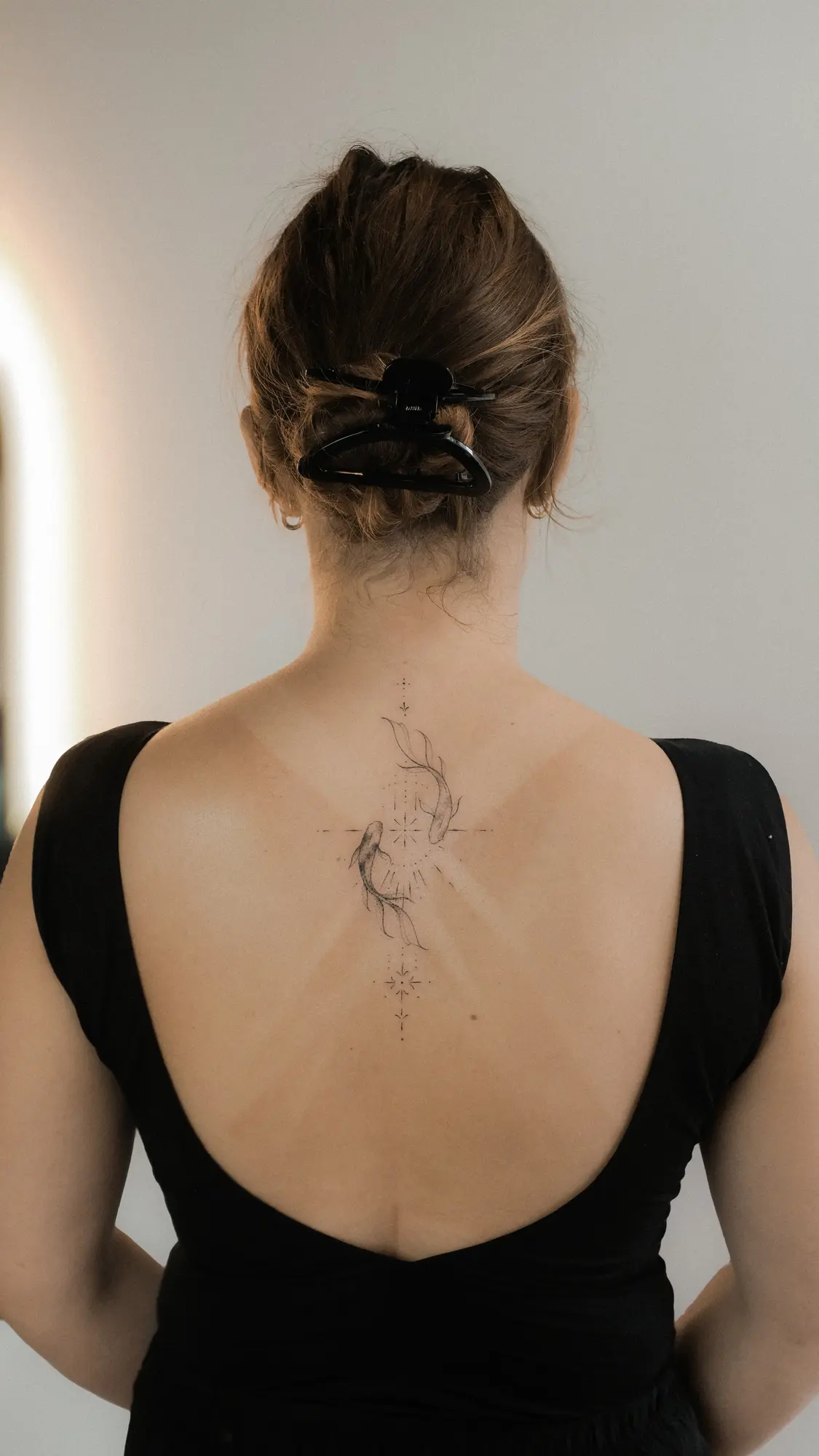 Delicate botanical tattoo flowing down the upper back
